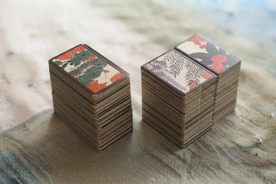 Two stacks of hwatu flower cards on a linen cloth.