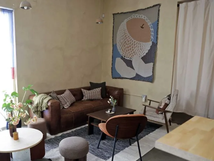 A living room with a low sofa and a fish tapestry on the wall.